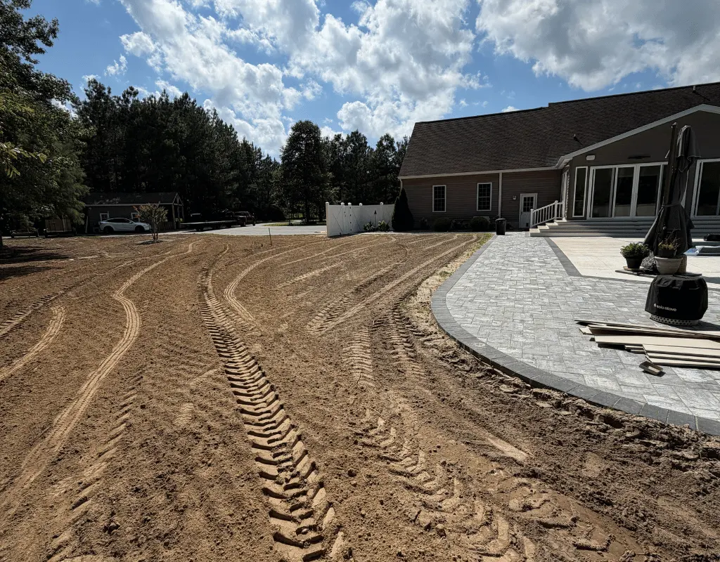 Freshly graded yard with track marks beside a house and stone patio on the Delmarva Peninsula